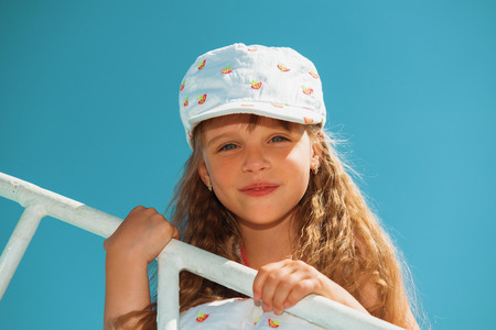 Portrait of little cute girl enjoying playing on boat on a hot sunny day. Beautiful smiling face.