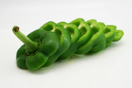 isolated green slightly cut sweet pepper on dishの写真素材