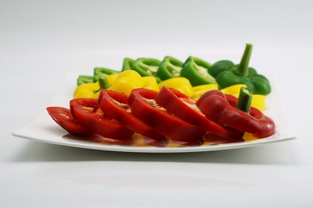 isolated set of slightly cut sweet pepper on dish