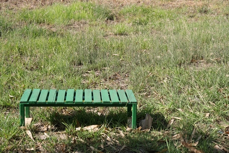 green bench on the grass field at noon time