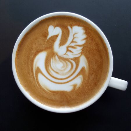 Top view of a mug of latte art coffee on black background.の写真素材