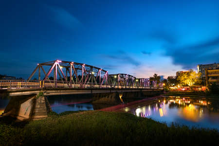 The historical iron bridge at Chiangmai city skyline at Ping river at dusk. Chiangmai , Thaland. Long exposure photograph.の写真素材