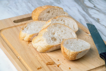 Fresh sliced baguette bread on marble table. Healthy eating breakfast.