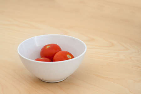 Tomatoes in a bowl on the tableの写真素材