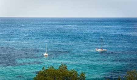 Mediterraneans scene. Turquoise crystal clear waters of Ibiza island.Two Sailing boat on the waterの写真素材