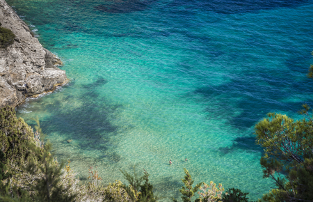 2 people swimming in a beautiful tropical beach with turquoise water and white sand, Ibiza island, Mediterranean sea.の写真素材