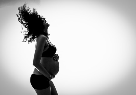 Beautiful pregnant woman - isolated over a white background. Young happy woman engoyinig motherhoodの写真素材