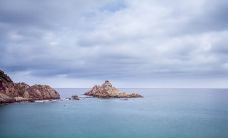 Cloudy sky and quiet sea and rocky coast.の写真素材