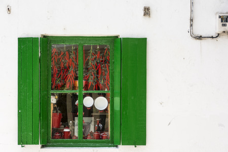 Dried red pepper hanging through a green the windowの写真素材