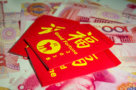 The red envelope or hong bao is used for giving money during the Spring Festival, or Chinese New Year in China and Taiwan. Envelope with the chinese words meaning Good fortune on it over yuan bills.の写真素材