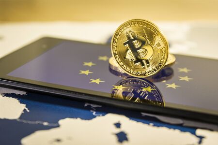 Financial concept with golden Bitcoin over smartphone, UE flag and map. Situation of Bitcoin and other cryptocurrencies in European Union concept.の写真素材