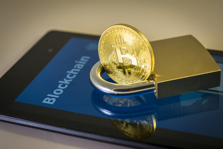 Bitcoin and padlock over a screen with blockchain word