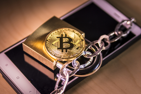 Bitcoin, padlock and chain over a screenの写真素材