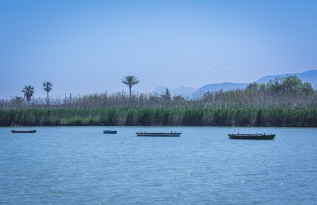 Calm lake with fishing boats. Fresh water lagoon in Estany de cullera. Valencia, Spainの写真素材