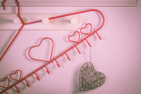 Pink Heart clothes hanger and heart shape hanger on red background. Valentines day conceptの写真素材