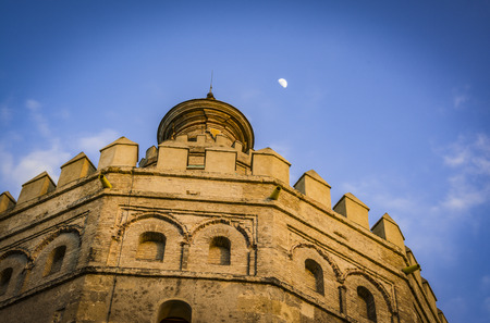 Low-angle shot of Torre del Oro at the blue hour with the moon on the background. Seville, Spainの写真素材
