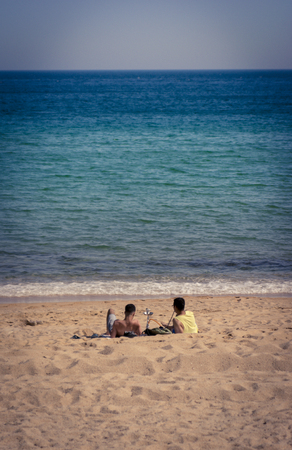 Two young man smoking shisha or hookah, sitting by the sea.の写真素材