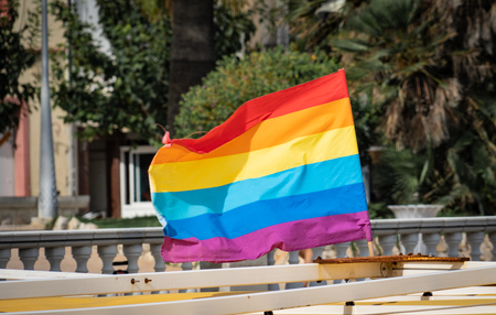 Gay pride flag blowing in the wind on Sitges Beach, Spain.の写真素材