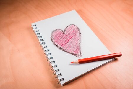 love heart on notebook with red pen on orange wooden table. Suitable for love, valentine,...