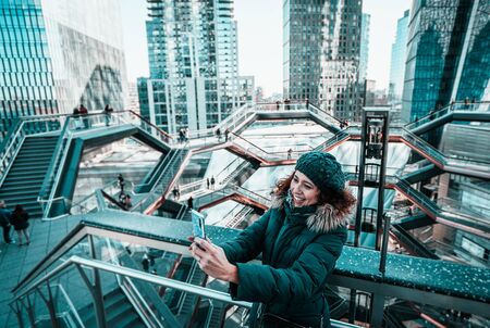 Beautiful curly brunette woman taking selfie self-portrait in The Vessel at the Hudson Yardsの写真素材