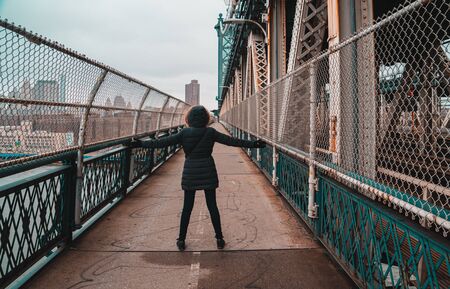 Tourist woman with warm clothes on the Manhattan bridgeの写真素材