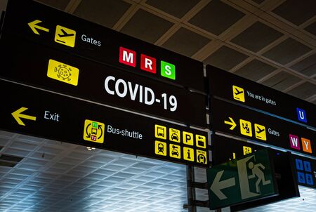 Information panel with Covid-19 word on it at an international airport.の写真素材