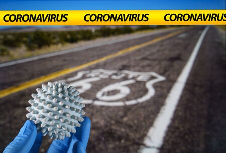 Coronavirus ball with US road with a Route 66 sign painted on it on the backgroundの写真素材