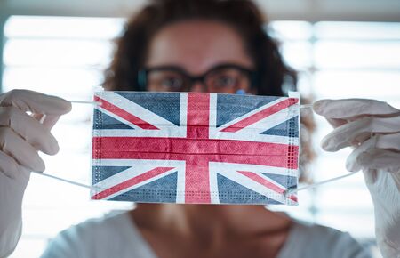 Pandemic Coronavirus. Close up of young woman with surgical mask with the flag of UK on itの写真素材