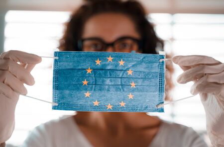 Pandemic Coronavirus. Close up of young woman with surgical mask with the EU flag on itの写真素材