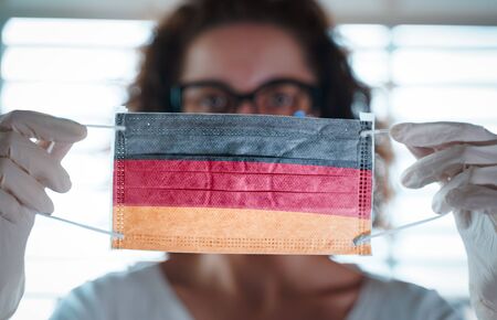 Pandemic Coronavirus. Close up of young woman with surgical mask with the flag of Germany on itの写真素材