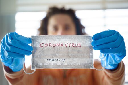 Pandemic Coronavirus. Close up of young woman with surgical mask and glovesの写真素材