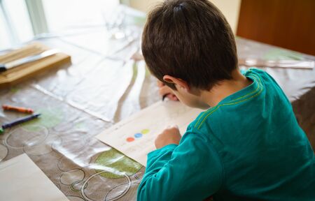 child drawing with crayons on paper or doing homework from homeの写真素材