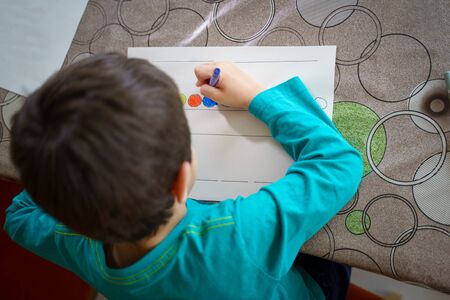 child drawing with crayons on paper or doing homework from homeの写真素材