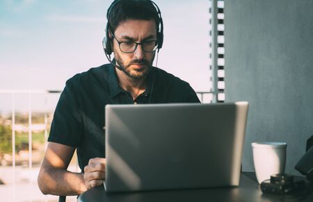 Man with headphones teleworking at home or travelingの写真素材