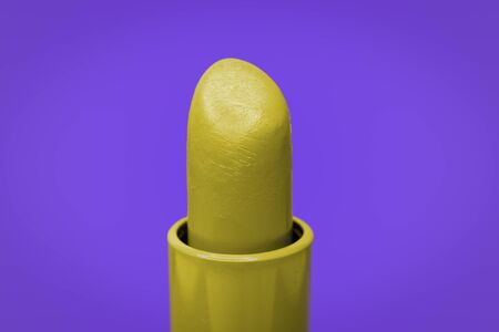 Beautiful bright yellow lipstick and purple complementary color on the backgroundの写真素材
