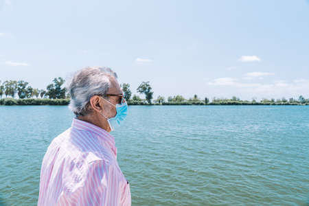 Senior man tourist wearing a disposable face mask during Covid-19の写真素材