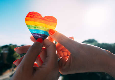lesbian couple holding hands and a rainbow heartの写真素材