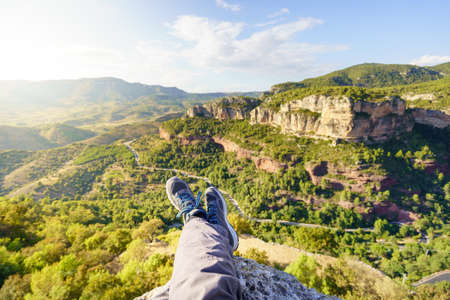First person perspective shot from a hiker sitting at the edge of a cliff at Siurana medieval town, catalonia, Spainの写真素材