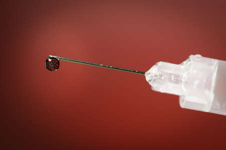 Close-up of a drop in a syringe with a 3D coronavirus inside.の写真素材