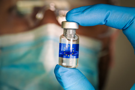 Close-up of medical vial with the EU flag and blurred doctor on the background.の写真素材
