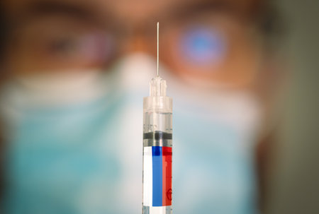 Close-up of hypodermic syringe with the russian flag and blurred doctor on the background.の写真素材