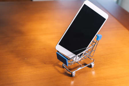 Smartphone inside a small shopping cart, online shopping conceptの写真素材