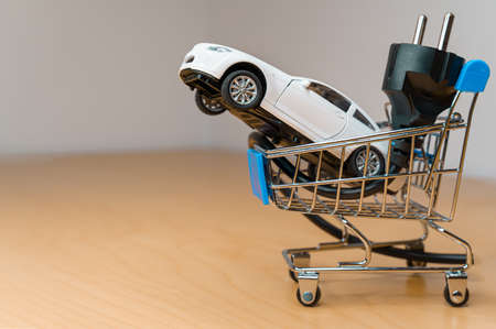 Toy car and electrical plug inside a small shopping cartの写真素材