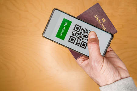 Man holding a passport and a Green pass certificate of vaccination.の写真素材
