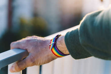 close-up view of a mans hand with an LGBT rainbow wristband.の写真素材