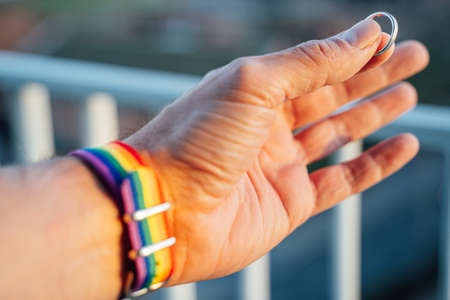 close-up view of a mans hand showing a ring with an LGBT rainbow wristband.の写真素材