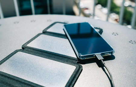Charging a smartphone from home with a portable solar panel charger.Self-consumption and charging with small solar panels iの写真素材