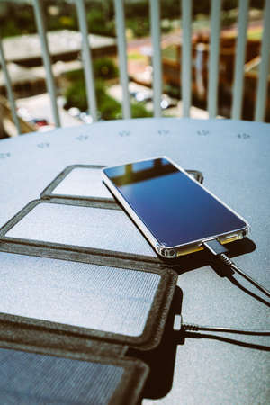 Charging a smartphone from home with a portable solar panel charger.の写真素材