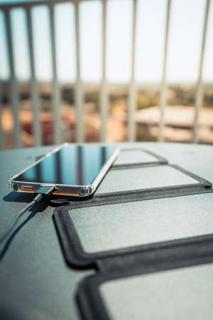 Charging a smartphone from home with a portable solar panel charger.の写真素材