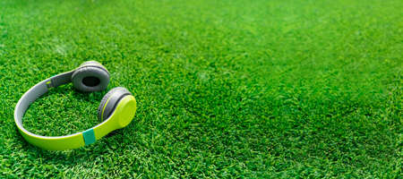 Green wireless headphones isolated on grass backgroundの写真素材